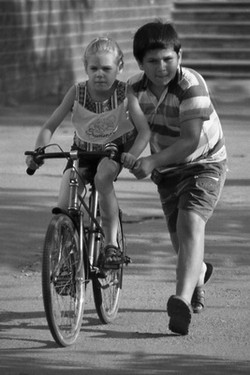 Брат учит сестру кататься на велосипеде