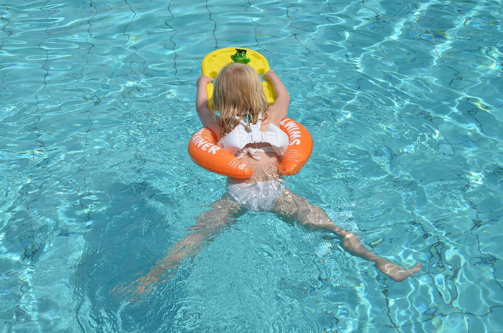 Маленькие купается бассейне. Круг Swimtrainer оранжевый. Девочки в бассейне. Оранжевый круг для купания. Дети в бассейне.